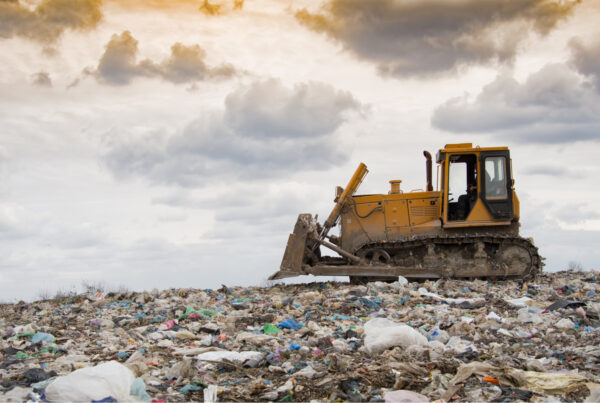 a bulldozer crushing waste at a landfill site