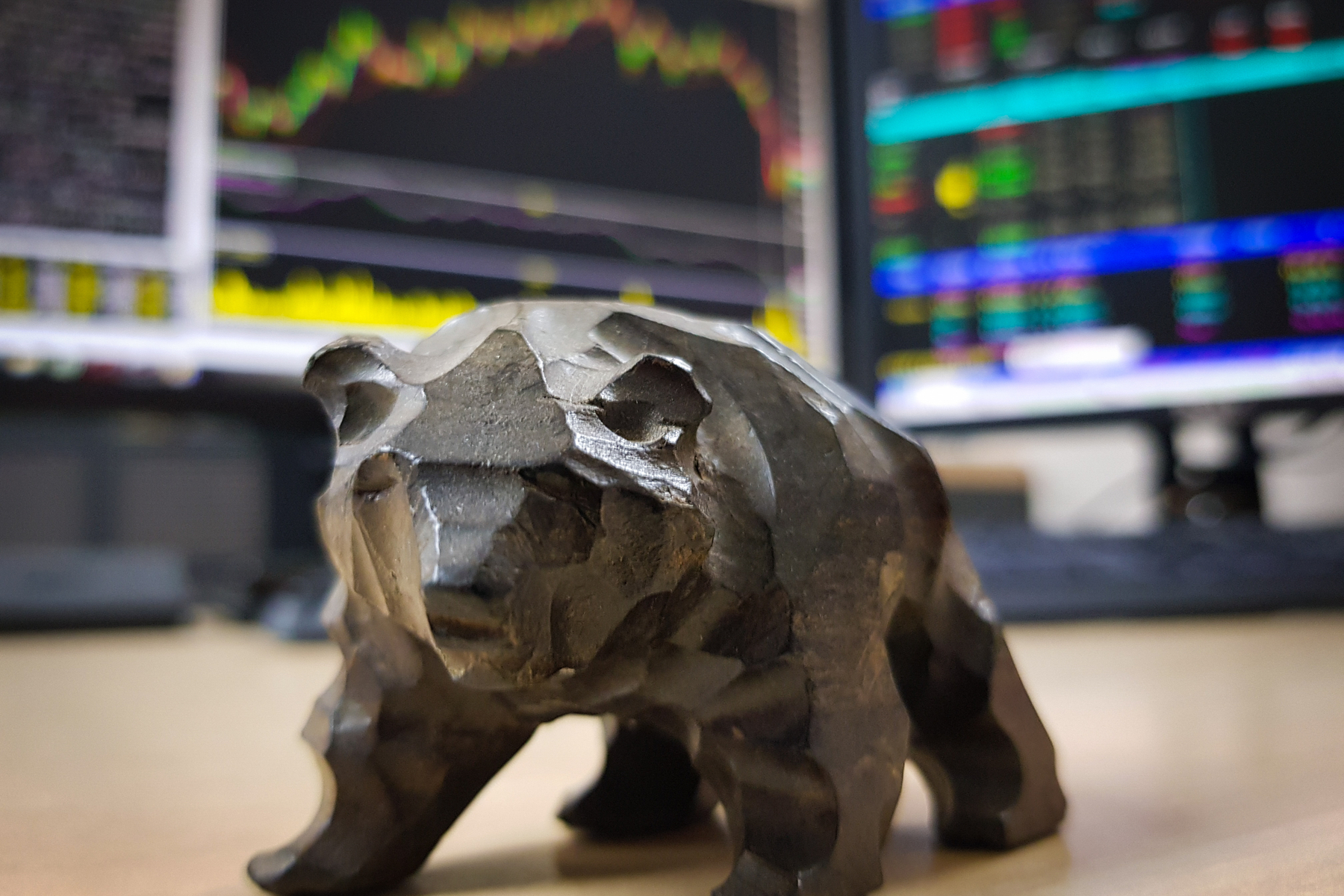 a figurine of a bear in front of investment graphs