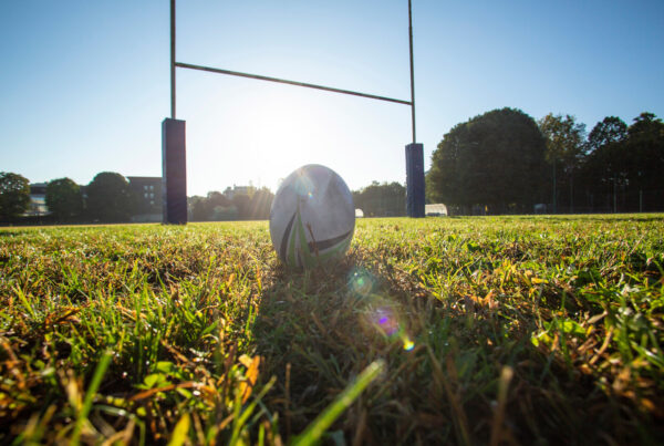 A rugby ball and posts on an empty pitch
